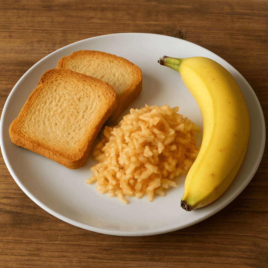 Ein Teller mit Zwieback, geriebenem Apfel und einer Banane auf einem Holztisch